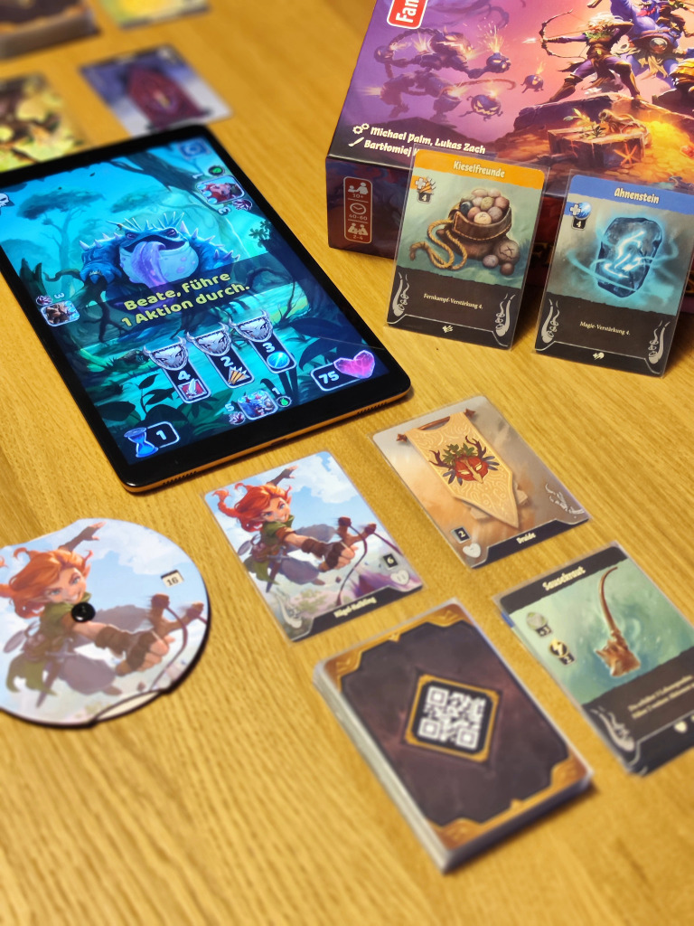 Spielmaterialien des Spiels Boss Fighters QR und ein Tablet auf einem Tisch.