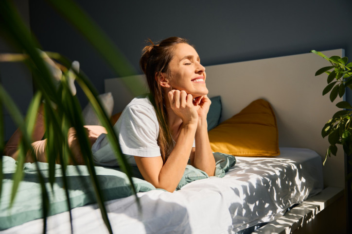 Eine Frau liegt auf dem Bett, sieht zufrieden aus und grinst breit.