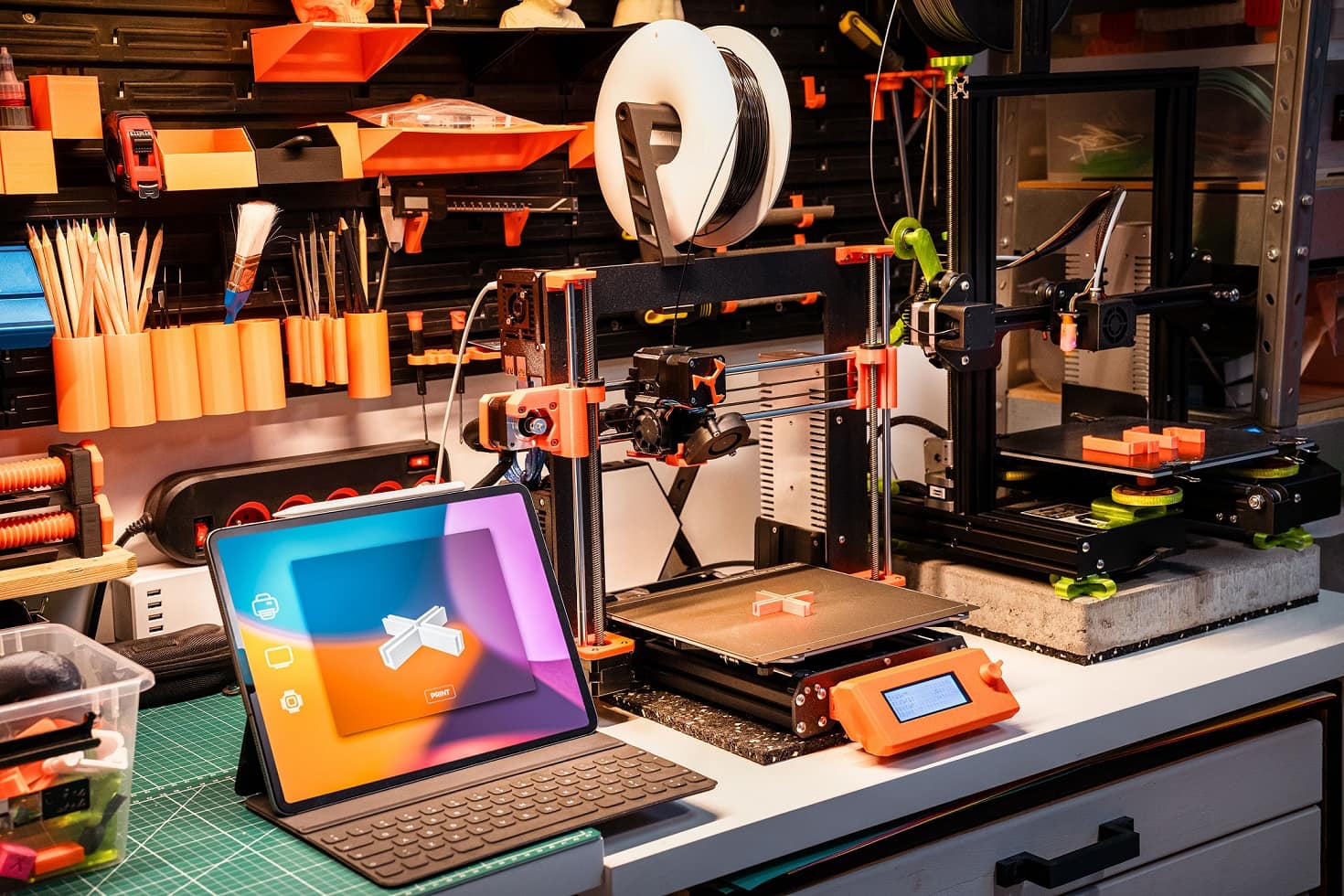 Zwei 3D-Drucker und ein Laptop stehen auf einem Schreibtisch